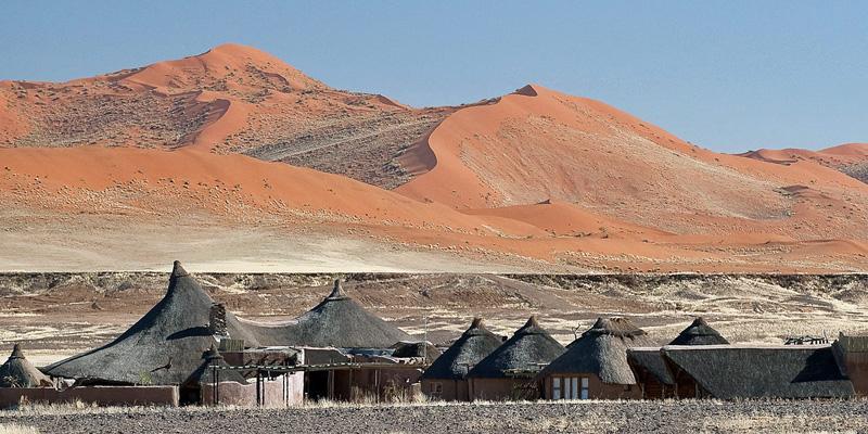 Massive red sand dunes in Sossusvlei, Namibia, with striking shadows and desert landscape.
